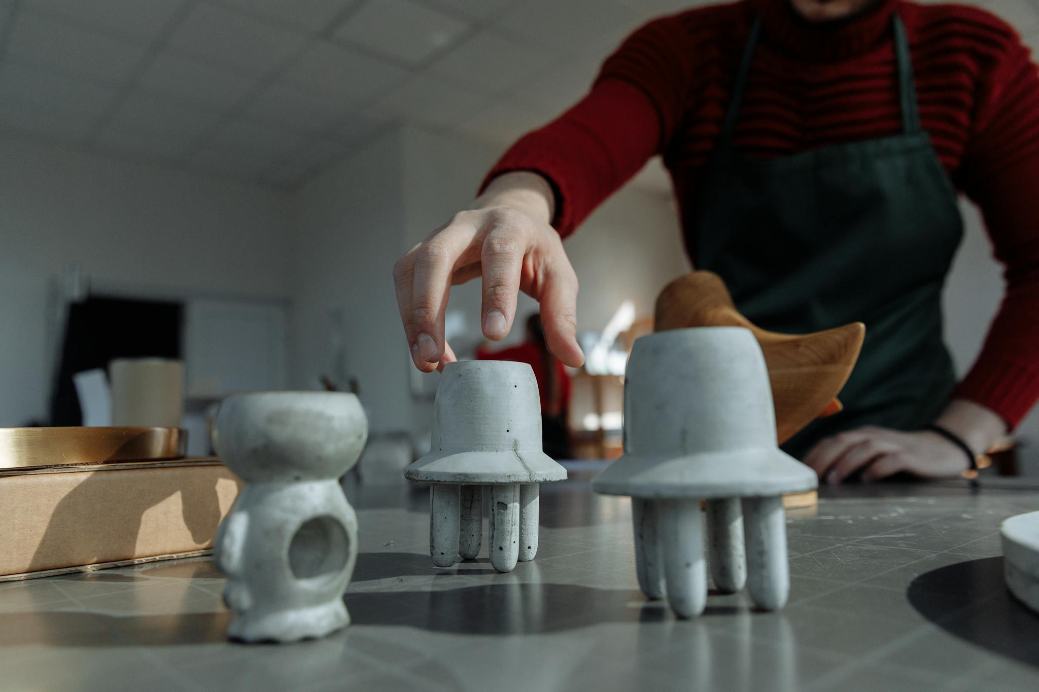 A close-up of a person sculpting unique handmade concrete figurines on a workshop table.