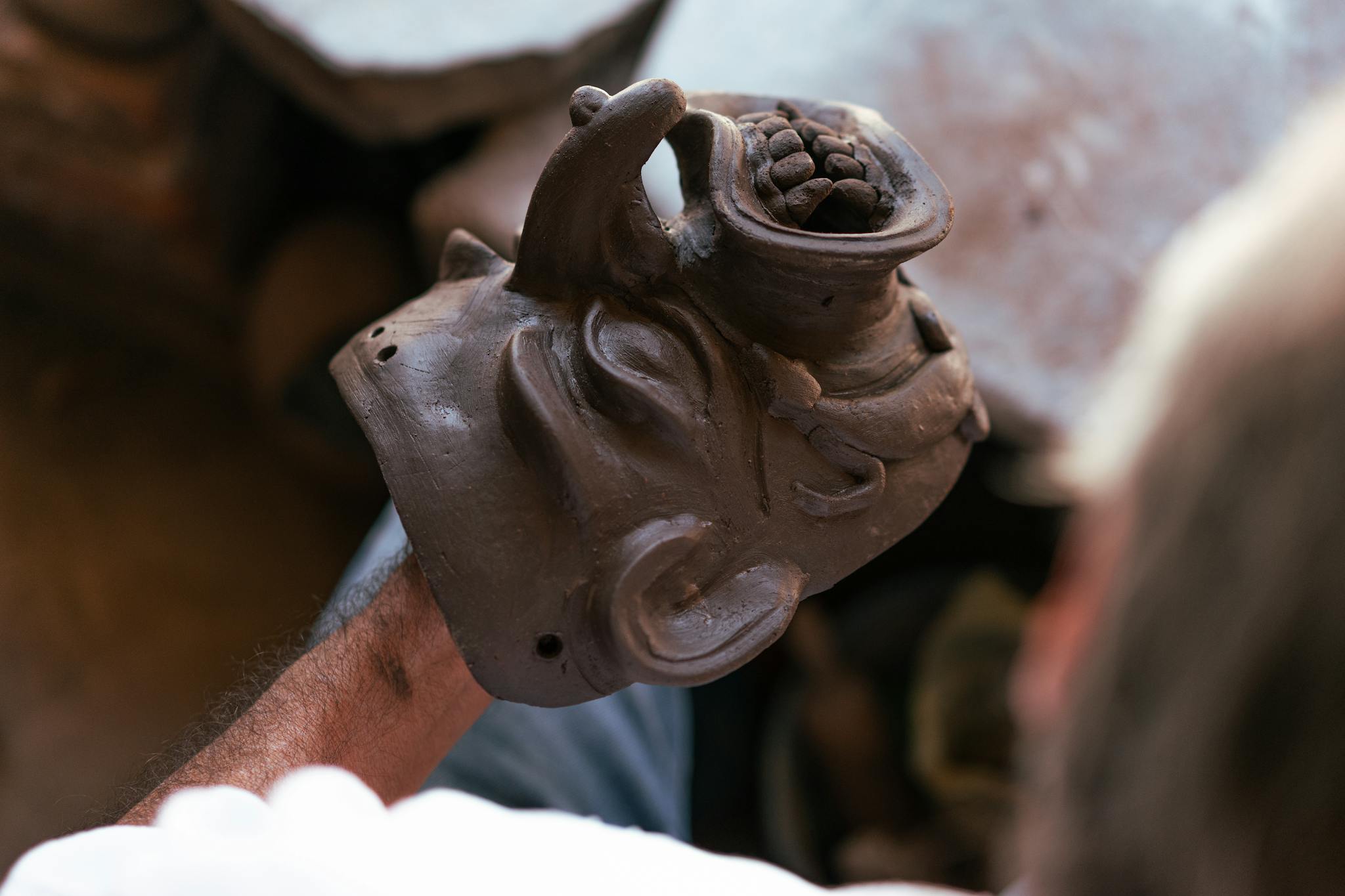 Artisan crafting a detailed clay mask, showcasing creativity and skill.