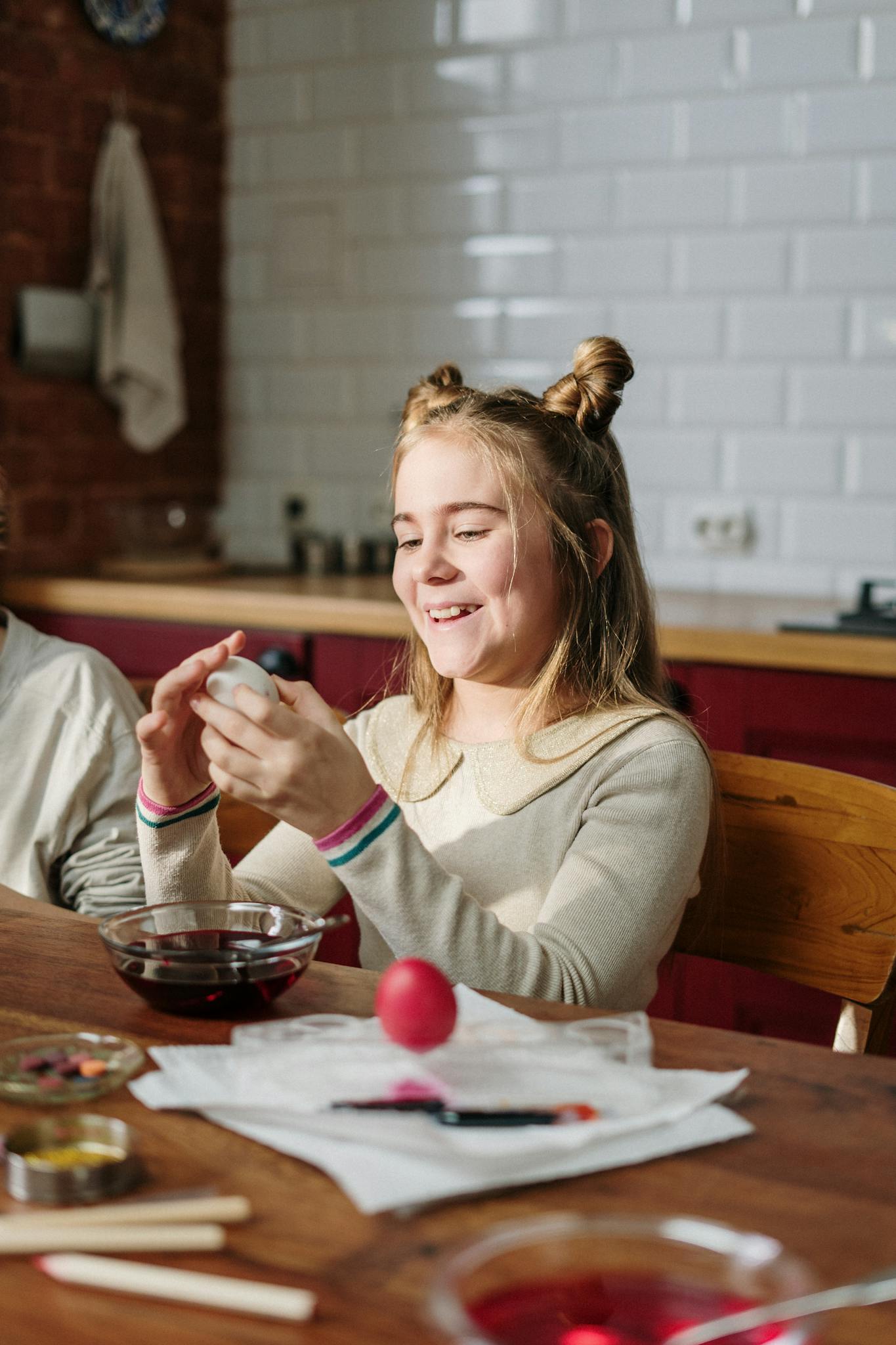 Child enjoying Easter egg decorating with family in cozy home kitchen.