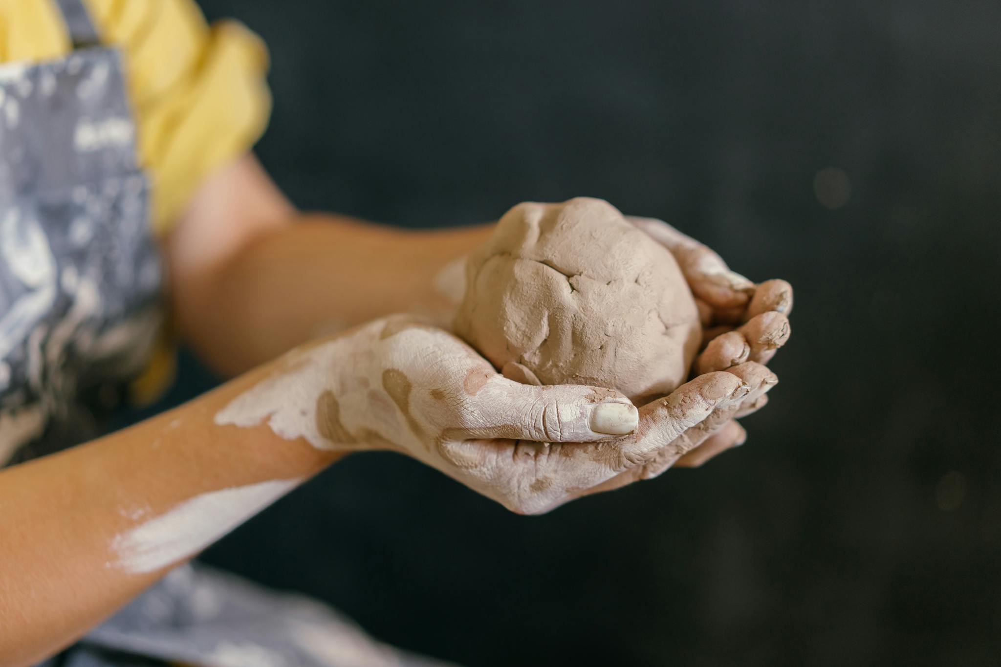 Close-up of hands molding clay, showcasing artistic pottery craftsmanship in progress.