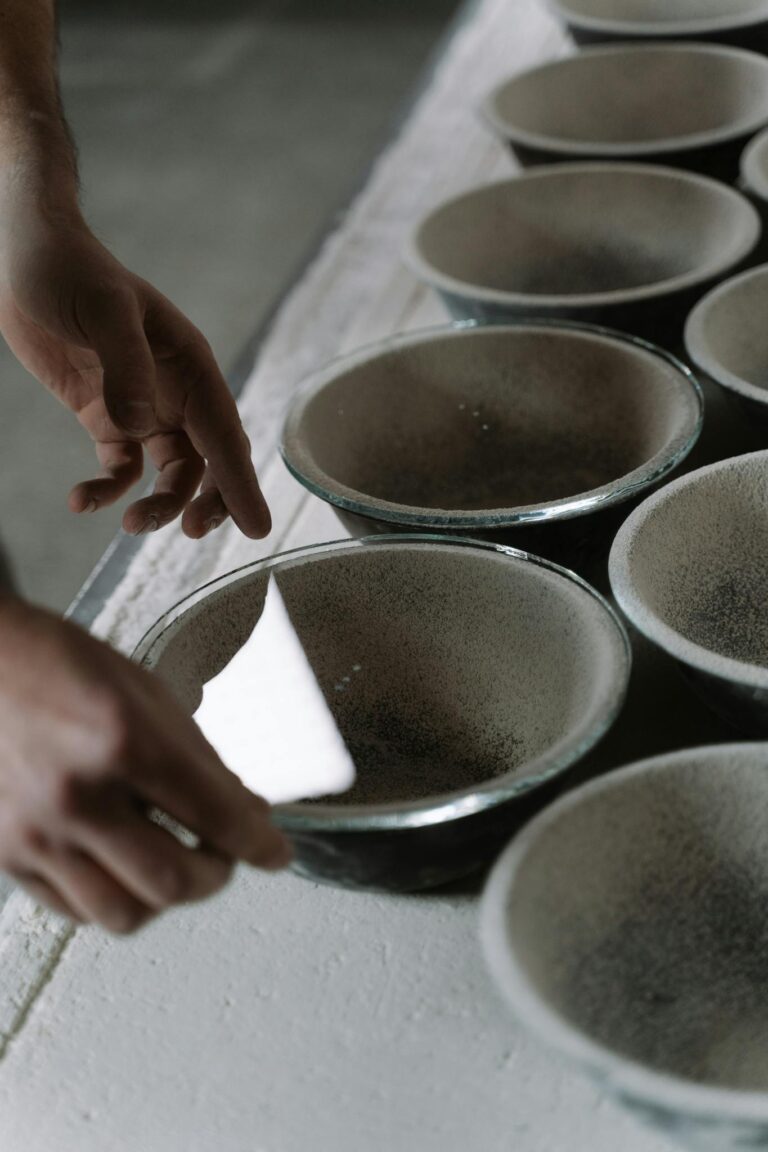 Close-up of hands shaping ceramic bowls in a workshop, emphasizing craftsmanship.