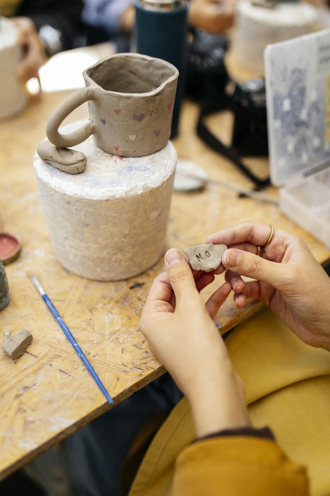 Person holding clay for handmade mug in artistic workshop environment.